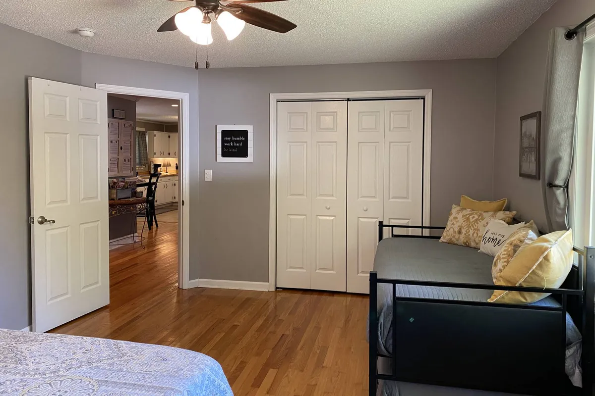 A cozy second bedroom displaying both a bed and a daybed with trundle, a closet with doors, and decorative pillows that add comfort. The space feels inviting for siblings or groups, with multiple sleeping options and accessible storage.