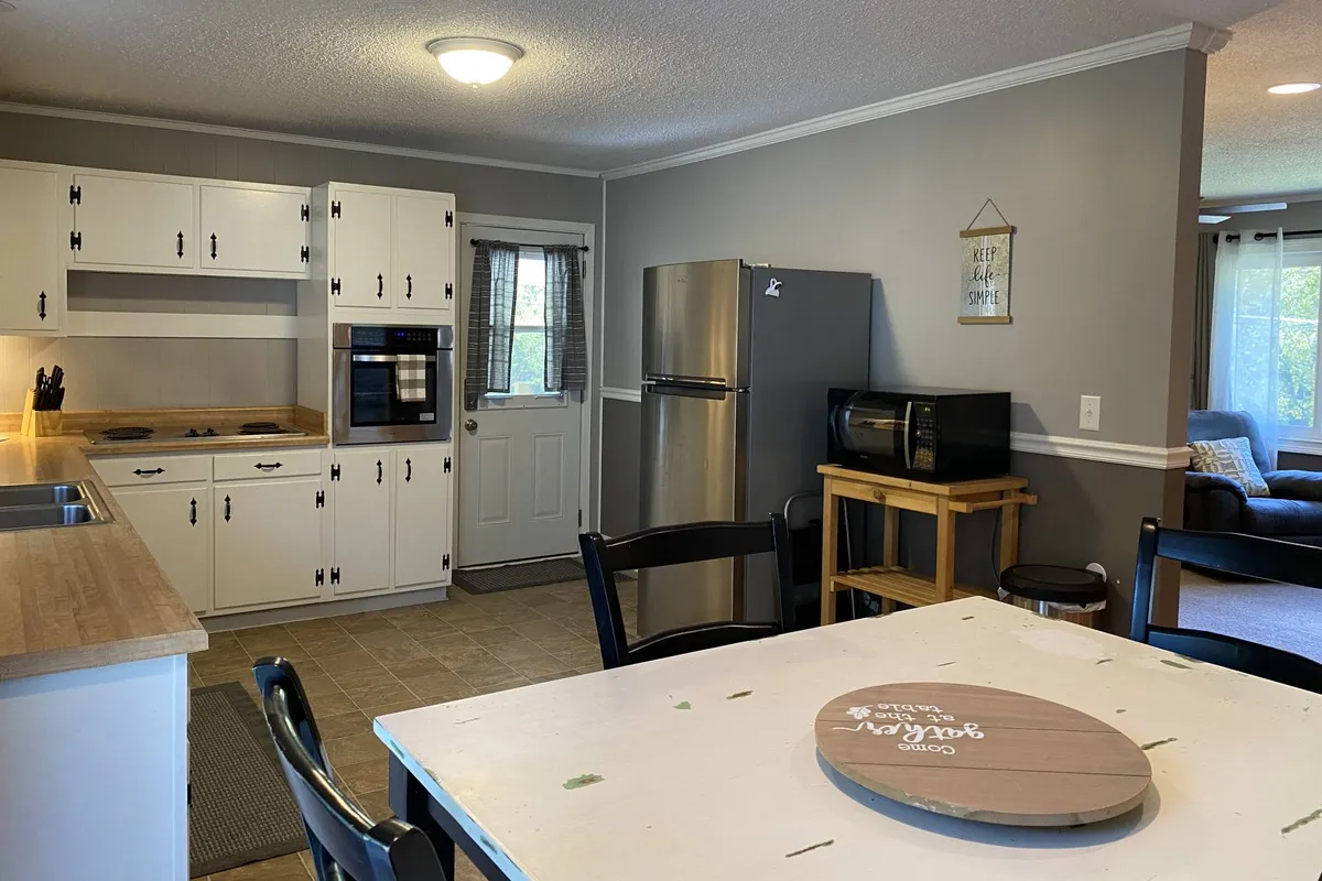 A comfortable and welcoming kitchen-dining scene, featuring a spacious countertop, dining table, refrigerator, and oven. The arrangement encourages socializing, family gatherings, and preparing meals together, aligning with the section's emphasis on connection and shared experiences.