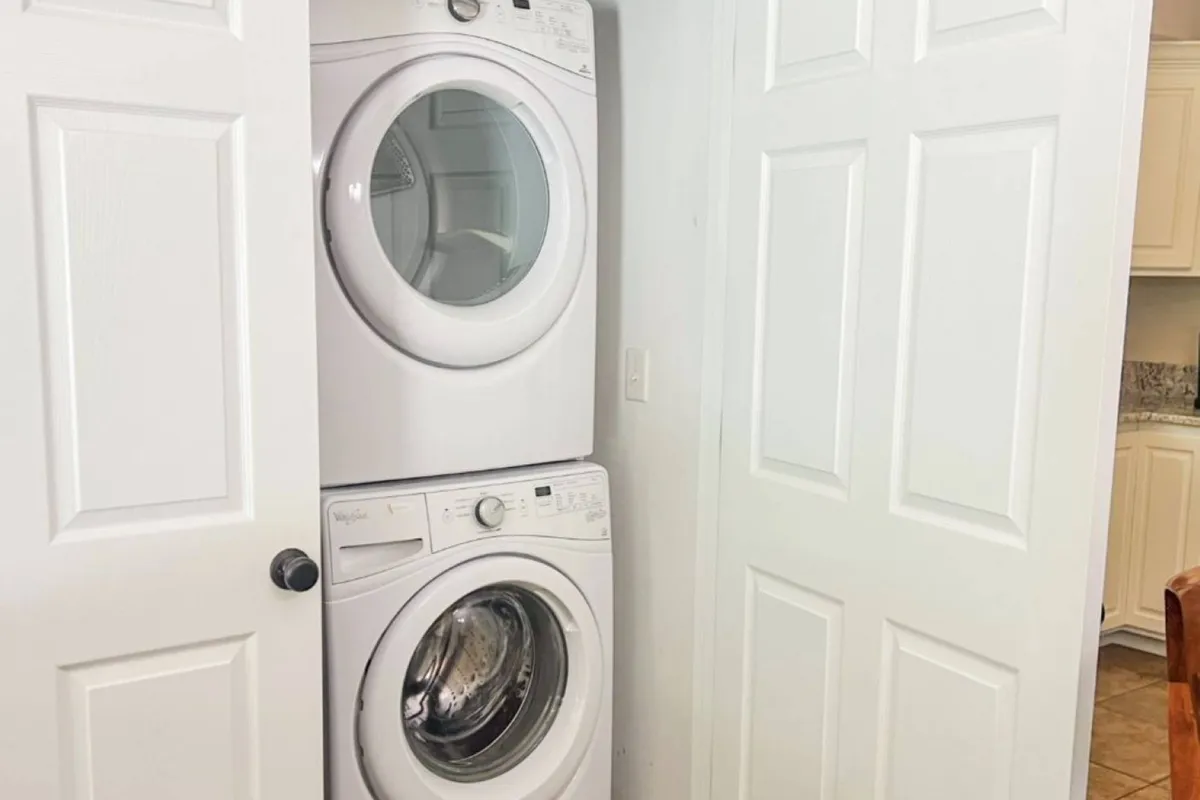 A tidy laundry area with a washer and dryer neatly tucked behind doors, emphasizing practicality and convenience for travelers. The space is clean and uncluttered, reflecting a well-equipped home base for adventurers returning from the outdoors.
